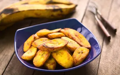 bananes plantains frites dorées dans une assiette bleue sur bois