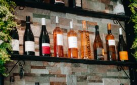 Assorted wine bottles on rustic stone shelves in a cozy setting.