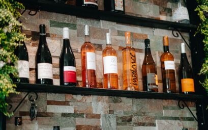 Assorted wine bottles on rustic stone shelves in a cozy setting.
