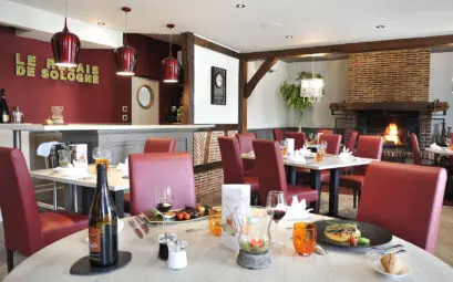 restaurant gastronomique en Sologne avec décoration rouge, cheminée et tables dressées
