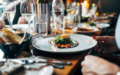 table de restaurant avec assiette gastronomique, verres de vin blanc et pain